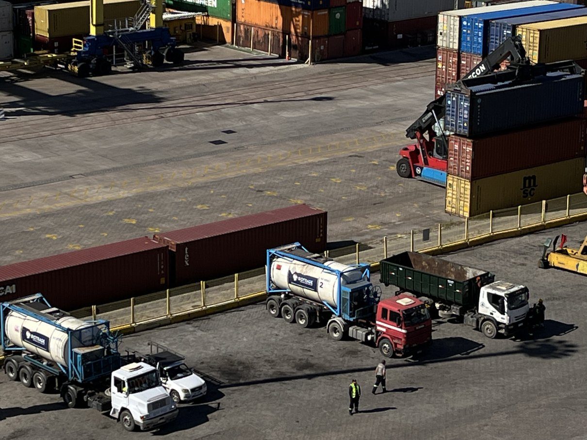 Lkw, Containerstapler und Arbeiter auf einem Hafengelände